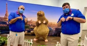 Cast Members in EPCOT’s signature blue shirts join Remy from Remy’s Ratatouille Adventure, all wearing masks and copying Remy’s playful paw pose, as they mark 60 days of culinary fun.