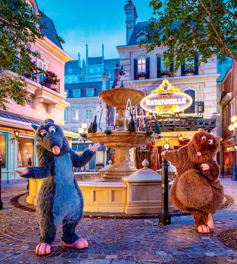 Remy and Emile greet guests in front of the iconic fountain at Remy’s Ratatouille Adventure, nestled in EPCOT’s Paris-inspired pavilion—just steps away from the enchanting festivities of Walt Disney World’s 50th Anniversary near Cinderella Castle, capturing a scene straight out of D23 Magazine.