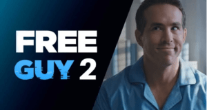 Free Guy, dressed in his signature blue shirt and grinning with anticipation, stands next to the vibrant “Free Guy 2” signage, setting a playful tone reminiscent of a theme park attraction as fans eagerly await the fun and adventure promised in the sequel.