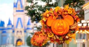 Festive Mickey Mouse pumpkin wreath adorned with autumn leaves, set against the iconic blurred Disney castle backdrop—celebrating Halloween magic at Walt Disney World.
