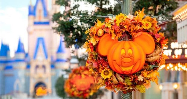 Festive Mickey Mouse pumpkin wreath adorned with autumn leaves, set against the iconic blurred Disney castle backdrop—celebrating Halloween magic at Walt Disney World.