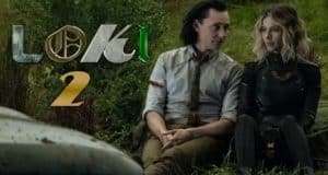 Loki and Sylvie relax on the grass near the vibrant "Loki 2" logo, evoking the feeling of a Marvel-themed attraction where fans eagerly hunt for Easter eggs woven into every detail, all under the playful gaze of a behind-the-scenes Director.