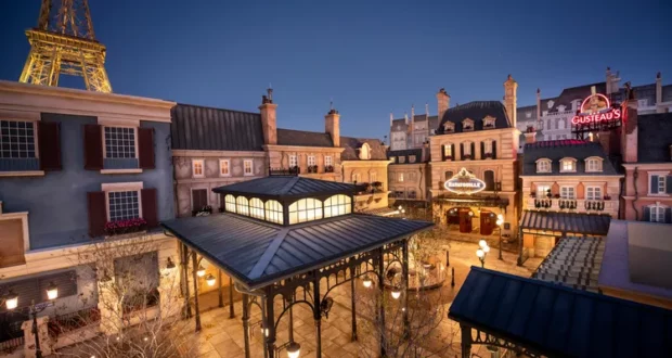 Remy’s Ratatouille Adventure courtyard at dusk, with the Eiffel Tower rising above twinkling patio lights and whimsical Parisian restaurant facades that capture the magic of Disney World.