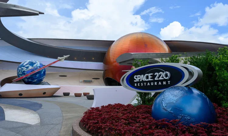 Entrance to Space 220 Restaurant at EPCOT, featuring impressive planet models and immersive space-themed decor against a bright blue sky, welcoming theme park guests to experience a galactic dining adventure.