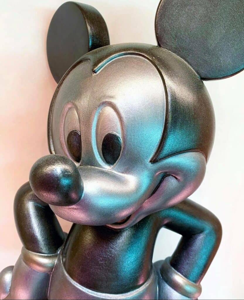 Mickey Mouse dazzles guests at the entrance of Creations Shop, striking a pose with one hand on his hip as a metallic silver statue gleaming with a mirror-like shine—a spectacular Mouse of Muse welcome in the heart of Disney World.