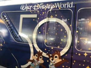 Monorail gliding through Walt Disney World, decked out with a sparkling “50” logo and playful Chip and Dale artwork, celebrating the Magic Kingdom’s 50th Anniversary in classic Disney style.