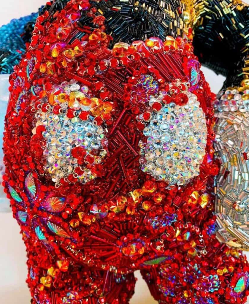 A dazzling, close-up view of a whimsical face crafted with sparkling red beads and sequins, capturing the playful artistry of Mouse of Muse Creations Shop—perfect for fans of imaginative theme park-inspired designs.