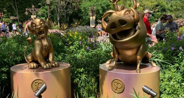 Simba, Timon, and Pumbaa from The Lion King are immortalized in shimmering bronze as part of the Disney Fab 50 Character Collection, proudly displayed on pedestals surrounded by lush gardens at Disney's Animal Kingdom.