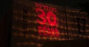The iconic "30 YEARS 30 FEARS" Halloween Horror Nights logo glows in bold red across the façade of Universal Studios, with barbed wire graphics adding to the event's signature eerie vibe.