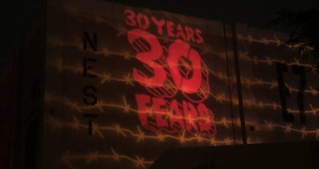 The iconic "30 YEARS 30 FEARS" Halloween Horror Nights logo glows in bold red across the façade of Universal Studios, with barbed wire graphics adding to the event's signature eerie vibe.
