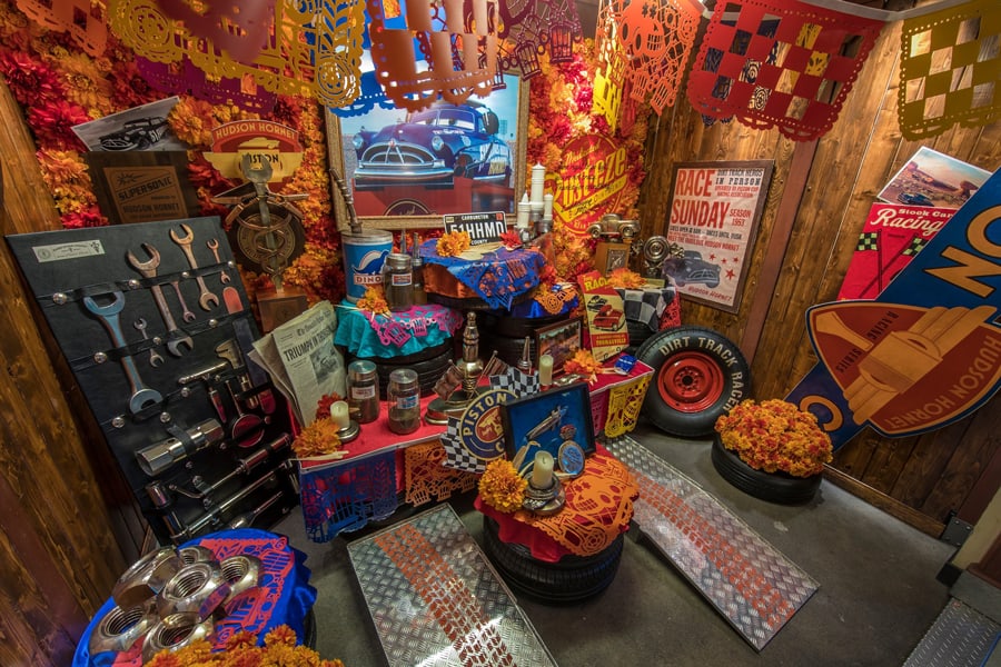Día de los Muertos altar at Disneyland Resort bursts with color and creativity, blending car parts, bright flowers, and papel picado for a Cars-inspired celebration. Guests can take in this one-of-a-kind display, where festive automotive accents meet classic Día de los Muertos traditions in true Disney style.