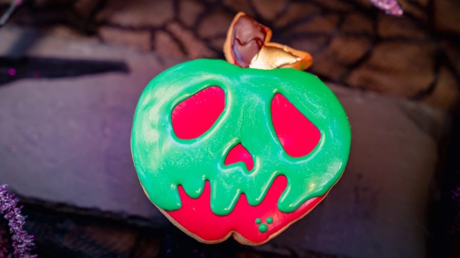 This dazzling Disneyland confection captures the magic of the parks—a vibrant red, apple-shaped dessert topped with neon green icing that drips to form an eerie poison skull, just like the legendary treat from Snow White.