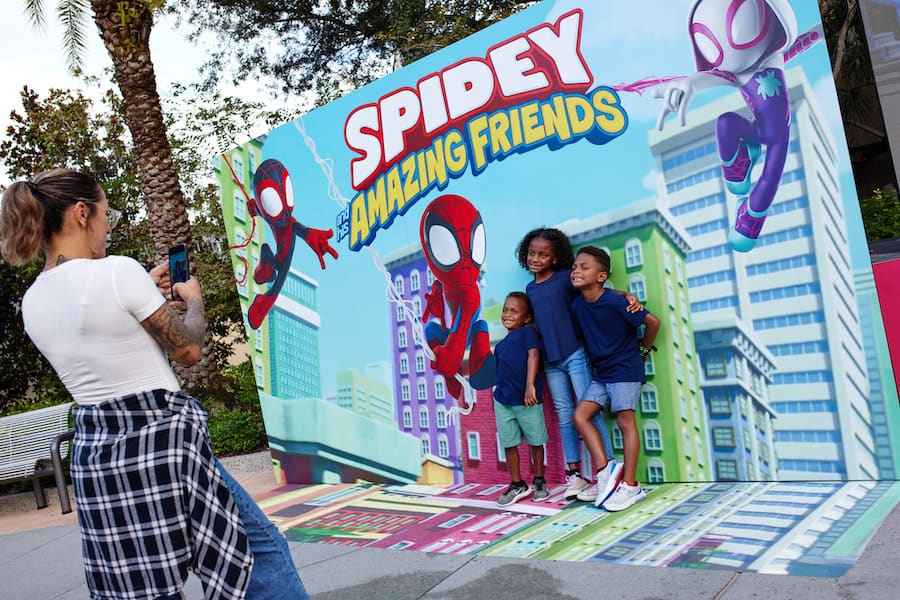 Guests capture a magical moment as three kids strike a pose in front of the Spidey and His Amazing Friends backdrop during the Disney Junior Pop Up event at Disney Springs.