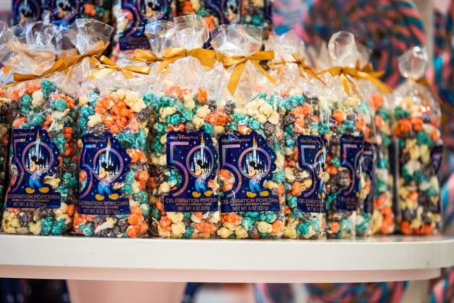 Colorful bags of "50th Celebration Popcorn" displayed on the shelves at Main Street Confectionery, freshly reopened in Magic Kingdom.
