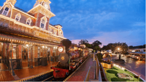 A classic Disney train pulls into a glowing Main Street Station beneath the iconic clock tower, surrounded by perfectly maintained gardens at sunset, evoking that magical Disney atmosphere you can expect when exploring what’s open at Disneyland this September.