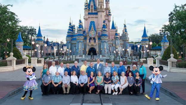 Members of the Class of 1971 gather in front of Cinderella Castle at Disney World, joined by Mickey and Minnie Mouse, to commemorate 50 years of Disney Magic.