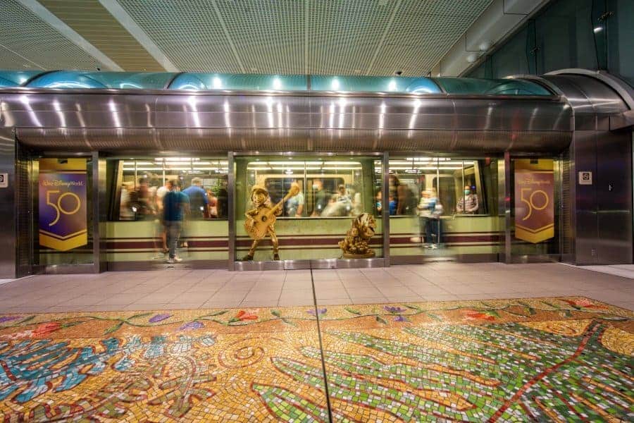 The Disney Monorail glides into the station, framed by vibrant 50th Anniversary banners and a dazzling mosaic floor—bringing the iconic magic of Walt Disney World’s grand celebration to life.