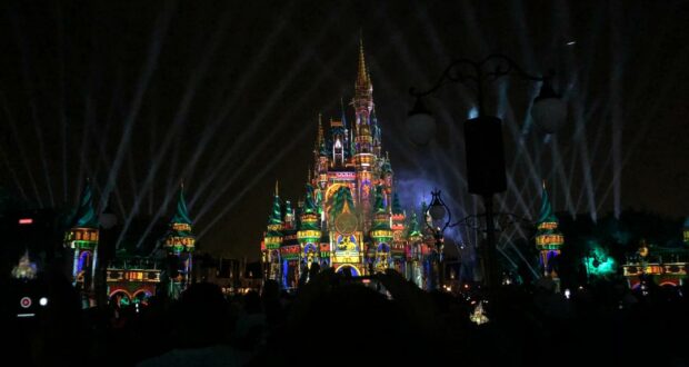 Cinderella Castle shines brilliantly at night, aglow with colorful lights and lasers, enchanting Magic Kingdom guests gathered below as dazzling fireworks explode above during the iconic Happily Ever After nighttime spectacular.