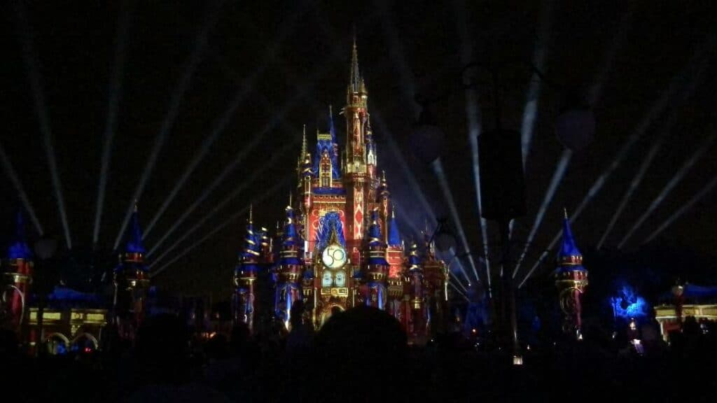 Cinderella Castle illuminated by vibrant lights and spotlights at night as Disney World guests gather to experience the breathtaking Happily Ever After fireworks spectacular on August 31, 2021.