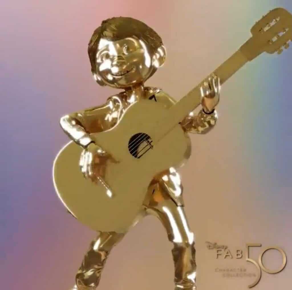 Golden statue of Miguel from Coco strumming his guitar, set against a pastel backdrop with "Disney Fab 50 Character Collection" displayed in the corner—part of Walt Disney World's anniversary celebration.