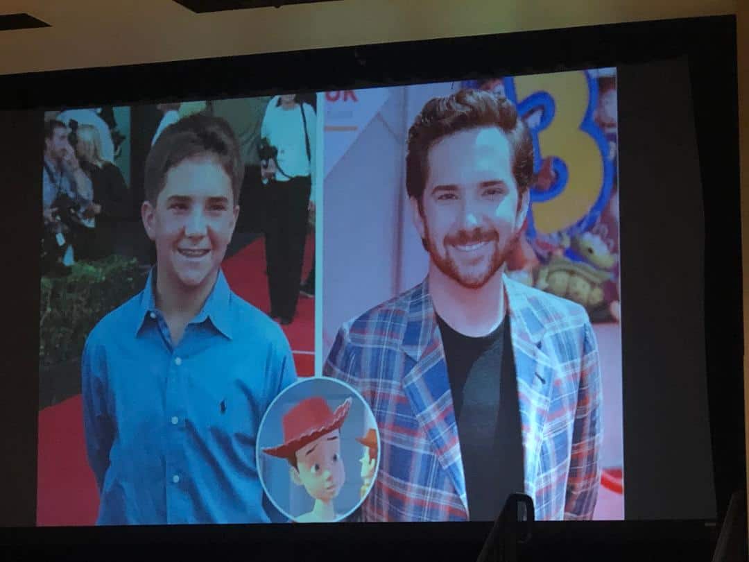 Split-screen showing a young boy and his grown-up self at a theme park, with Woody from Toy Story animated between them in the vibrant, comic-style art of John Morris.