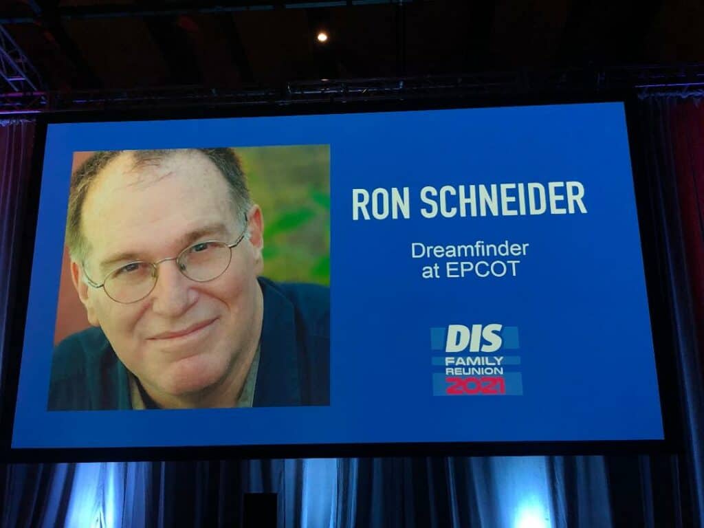 Ron Schneider, known as EPCOT’s original Dreamfinder, is featured on a panel screen with his photo and “Dreamfinder at EPCOT” text during a celebration of classic theme park attractions.