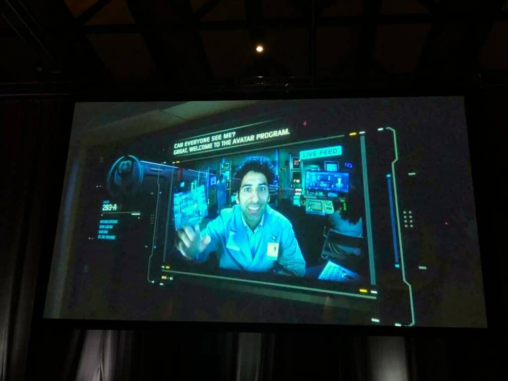 The interactive Actor Panel showcases a live-feed broadcast of a lab-coated scientist on a high-tech screen, surrounded by dynamic digital graphics as part of the attraction’s immersive entertainment experience.