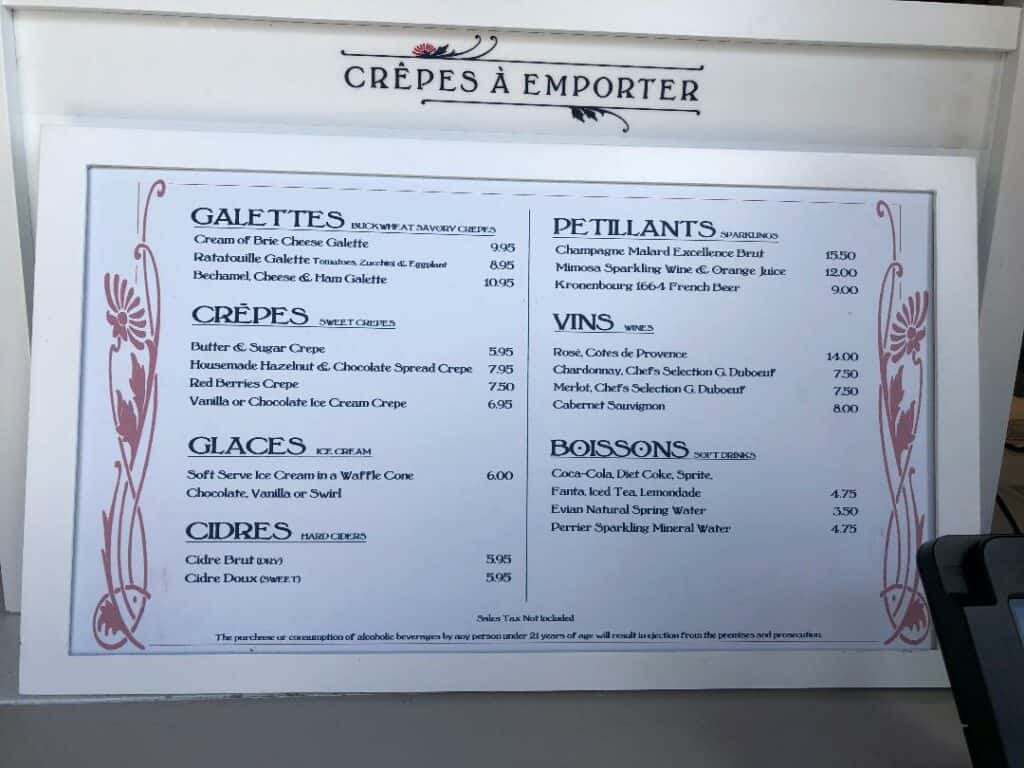 Whimsically designed menu board at Remy's Ratatouille Adventure, showcasing crêpes, galettes, drinks, wines, and desserts beneath elegant floral décor—capturing the enchanting Parisian ambiance of the attraction.