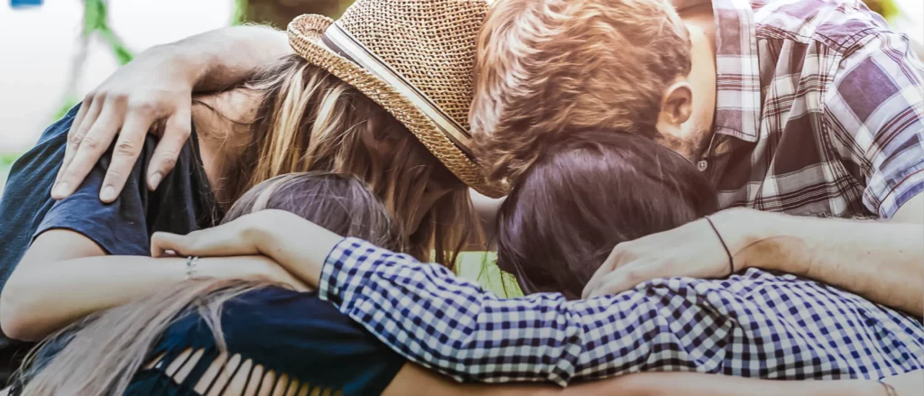 Fans gather outside Universal Studios Florida, kneeling together in a tight group hug with heads touching and arms around each other, buzzing with excitement as they share details about the newly announced Rock the Universe event.