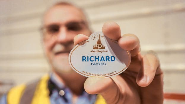 A Cast Member proudly displays a Walt Disney World name tag that reads "Richard, Puerto Rico," celebrating the diverse and vibrant backgrounds that make the Disney magic possible.