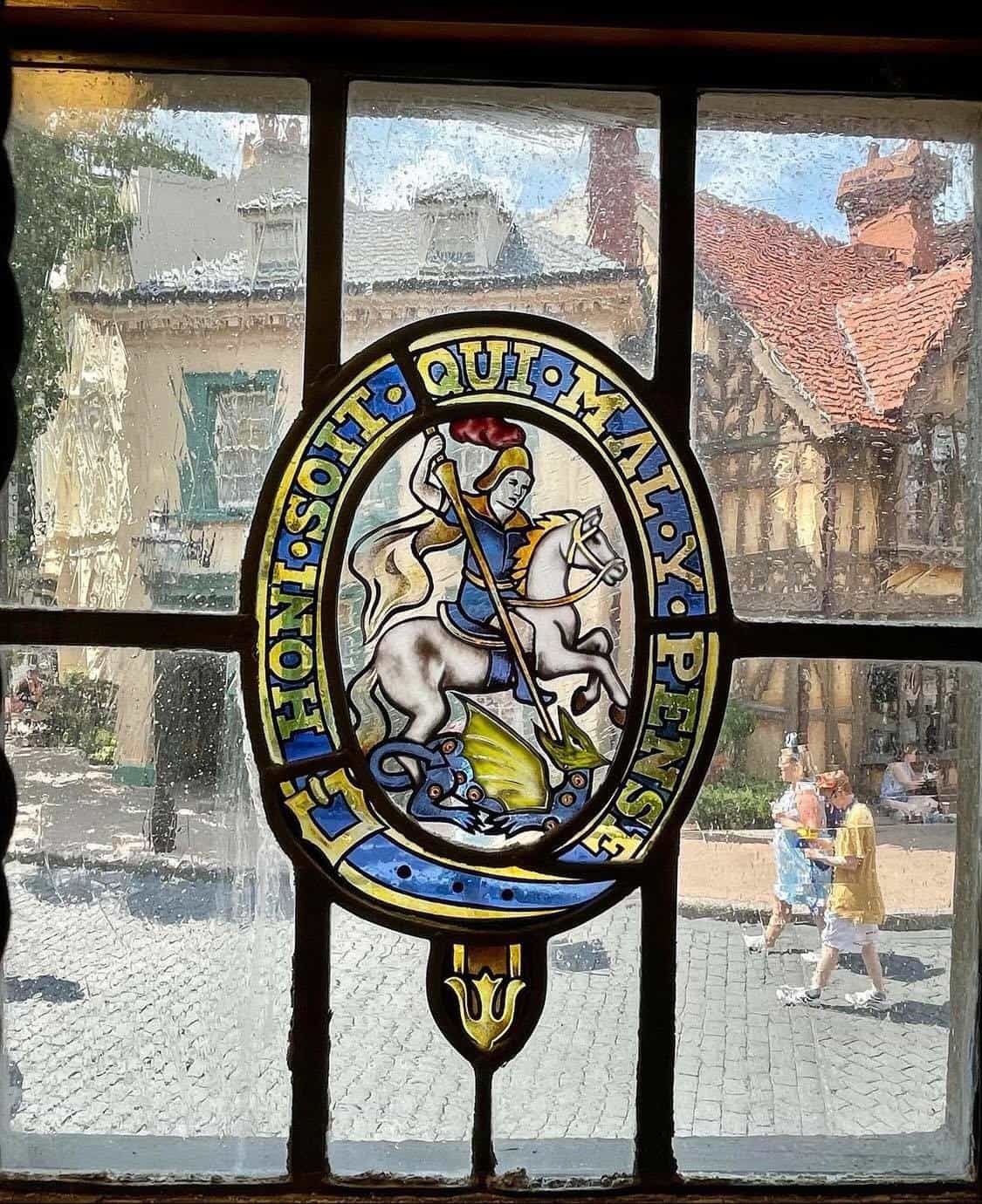 A stunning stained glass window in the United Kingdom Pavilion depicts a brave knight defeating a dragon beneath the words "Honi soit qui mal y pense," offering EPCOT guests an eye-catching and immersive new detail to discover.