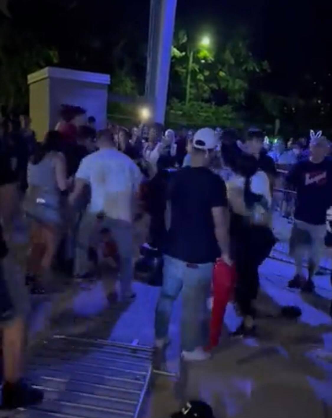 Guests cluster at night beside a metal barricade at Universal Studios, some engaging in a tense exchange that feels straight out of Halloween Horror Nights' most suspenseful moments.