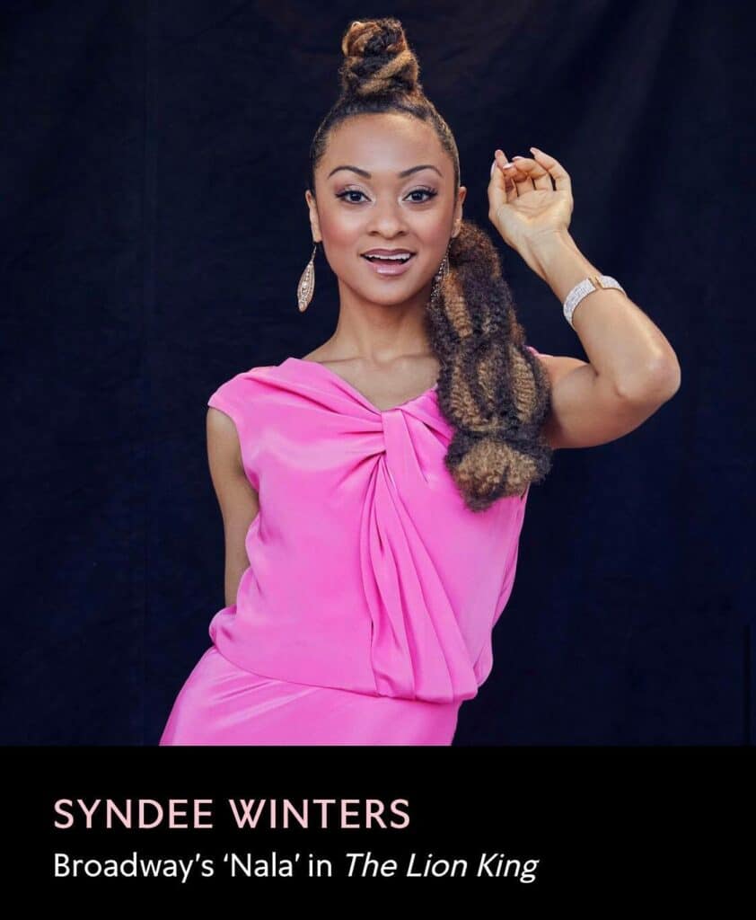 Syndee Winters, known to Disney fans as Broadway’s ‘Nala’ and a celebrated performer from Disney Princess the Concert, beams with excitement in a vibrant pink dress against a dramatic black backdrop. Text on the image highlights her Disney stage legacy.