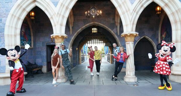 Mickey and Minnie Mouse greet five guests in front of the castle at Disney World, celebrating the enchanting atmosphere of Disney Nights with a flair that evokes Dancing with the Stars.