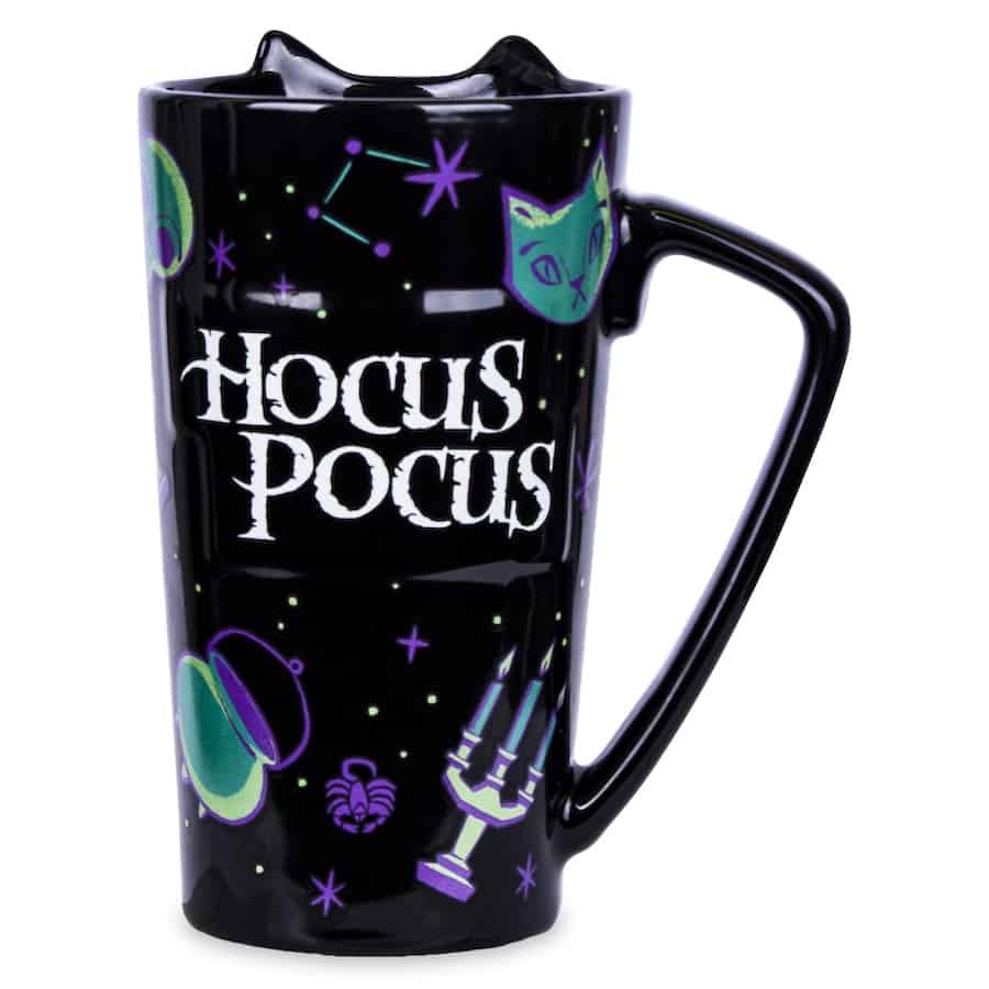 Hocus Pocus-themed black mug available in the parks, featuring a bold green cat face surrounded by constellation patterns, spiders, and whimsical purple and green designs perfect for fans of the Sanderson Sisters.