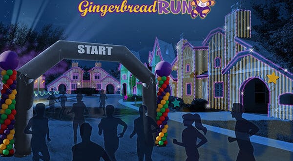 Gingerbread Run participants dash past whimsical, brightly lit holiday cottages inside Give Kids the World Village during a nighttime charity race, their silhouettes outlined by festive lights in a magical theme park setting.