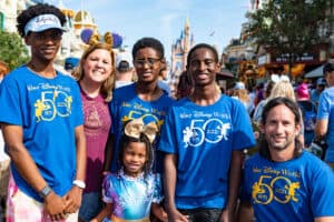 Six friends gather in front of Cinderella Castle at Disney World, joyfully celebrating the park’s 50th anniversary with festive energy.