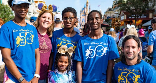 Six friends gather in front of Cinderella Castle at Disney World, joyfully celebrating the park’s 50th anniversary with festive energy.