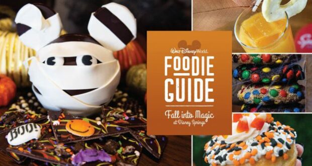 Halloween-themed Mickey mummy treat and festive desserts on display alongside a vibrant orange "Foodie Guide" sign, inviting guests to indulge in Magic Treats at Disney Springs.