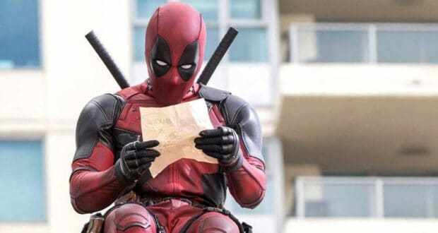 A performer dressed as Spider-Man reads a paper while relaxing outside Avengers Campus.