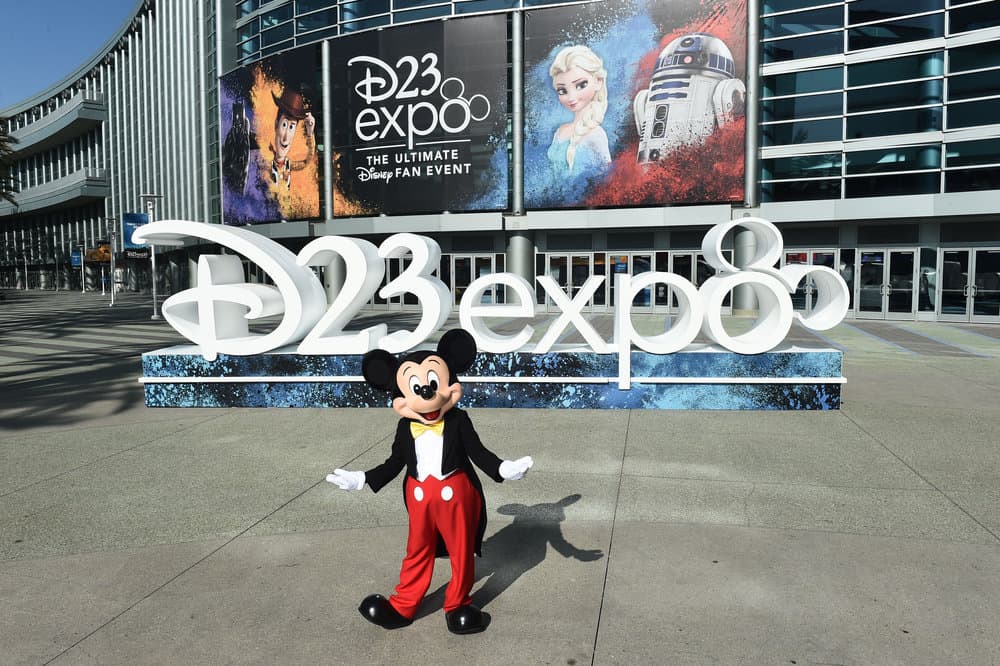 Mickey Mouse greets fans in front of the massive "D23 Expo" sign outside the convention center, surrounded by vibrant Disney banners that set the stage for this ultimate gathering of Disney enthusiasts.