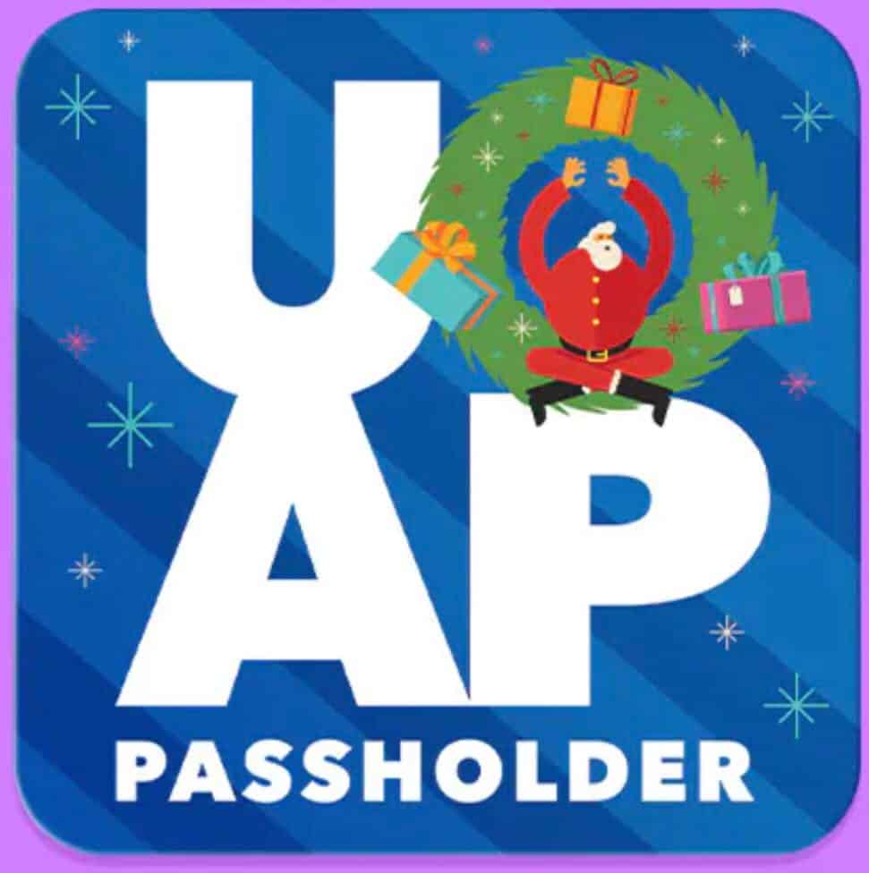 Santa sits cheerfully in a festive wreath surrounded by presents, set against a blue backdrop, as Universal Orlando celebrates exclusive Holiday Passholder Perks.