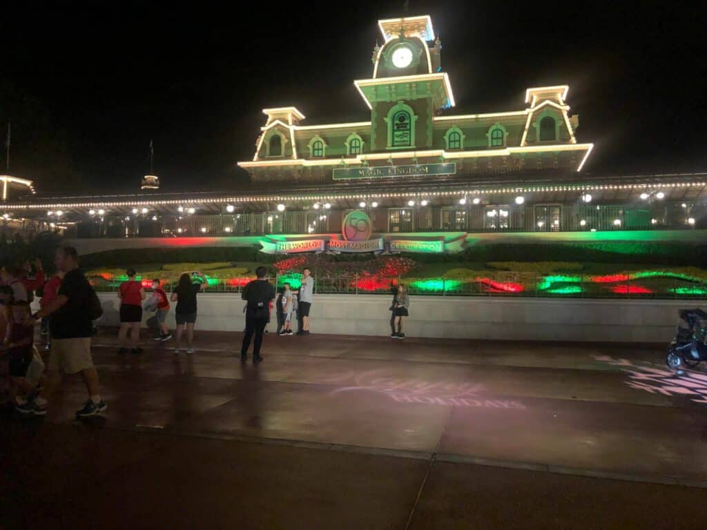 Guests gather at night beneath the dazzling, holiday-adorned Magic Kingdom entrance, debating whether Disney Very Merriest After Hours lives up to the enchanting reputation, as Main Street sparkles and promises an unforgettable, exclusive park experience.