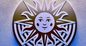 The iconic smiling sun from Drawn to Life beams with playful rays across a vibrant, patterned backdrop, radiating the cheerful energy and whimsical spirit that guests love in themed attractions.