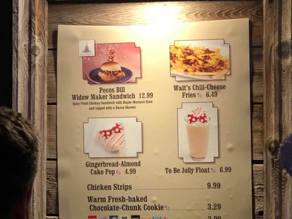 Festive menu board showcasing Disney Very Merriest After Hours treats: chicken sandwich, chili-cheese fries, cake pop, and a float—all with special holiday prices. Perfect for fans looking to savor these themed bites and snacks as part of the ultimate seasonal celebration at the park.