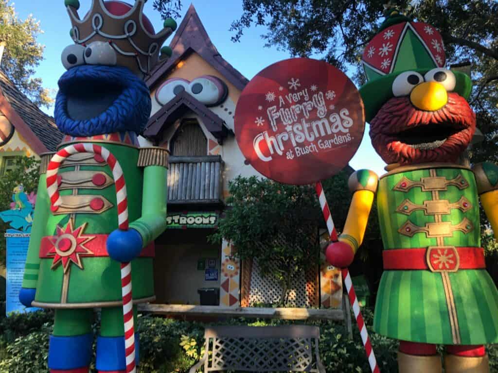 Giant nutcracker figures welcome guests at the entrance of Busch Gardens Christmas Town, holding candy canes and surrounded by dazzling holiday decorations that set the scene for a magical seasonal experience.