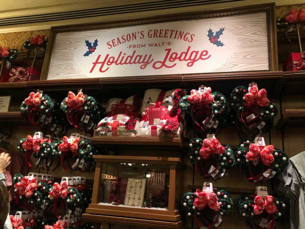 Disney’s Holiday Lodge-themed merchandise display shines with festive Minnie ears and cheerful wreaths beneath the eye-catching "Holiday Lodge" sign, inviting guests at Very Merriest After Hours to discover unique holiday merch and magical seasonal treats that elevate the park’s winter celebrations.
