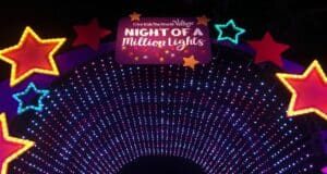 A dazzling arch of vibrant lights adorned with red stars and a glowing "Night of a Million Lights" sign illuminates the night sky at Give Kids the World Village, creating a magical entrance to one of Central Florida’s most spectacular holiday events.