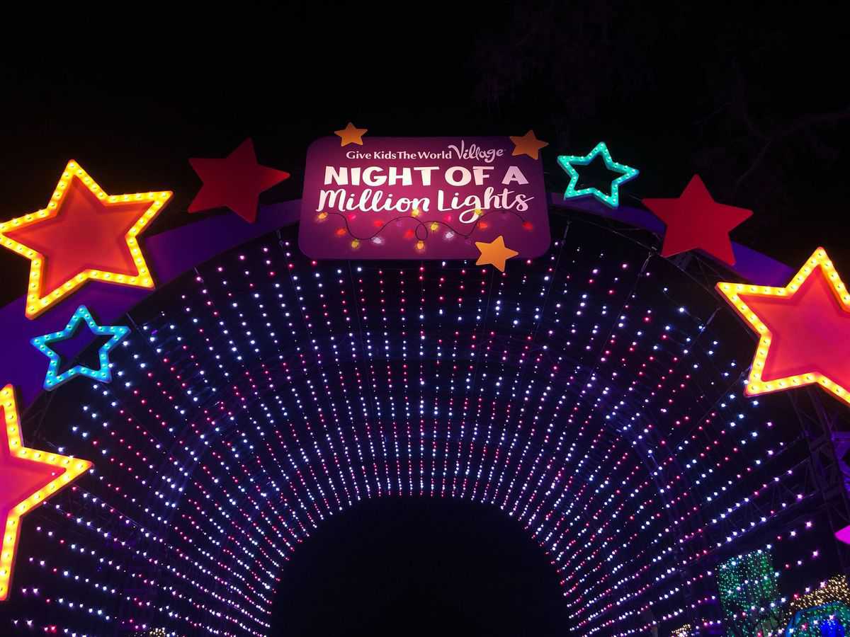 A dazzling arch of vibrant lights adorned with red stars and a glowing "Night of a Million Lights" sign illuminates the night sky at Give Kids the World Village, creating a magical entrance to one of Central Florida’s most spectacular holiday events.