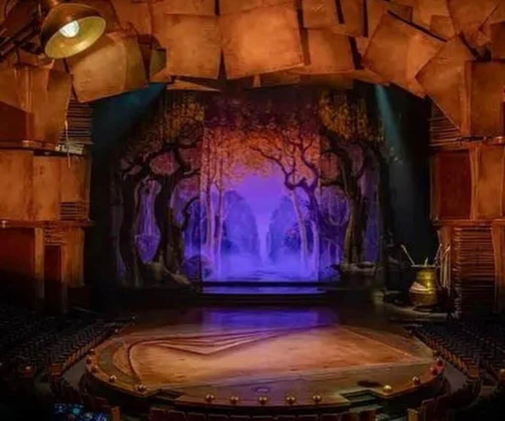 Experience the enchantment as Drawn to Life premieres, with the stage set against a vibrant purple forest backdrop, framed by brown panels and illuminated by theatrical lighting—bringing the magic of Cirque du Soleil and Disney to life for theme park guests.